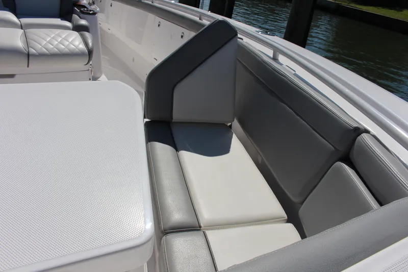 Slide: The Image of 2024 Everglades 395 Center Console boat seating area with gray cushions and table. - 16