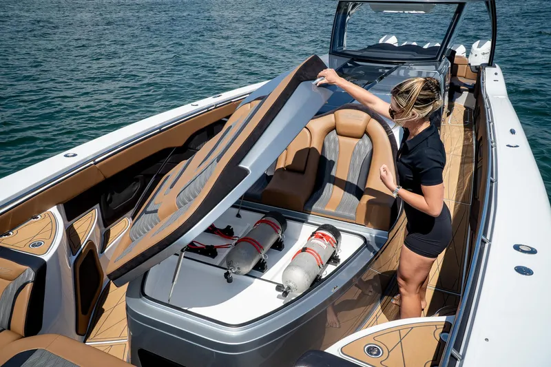 Slide: The Image of 2022 MTI V50 boat with open storage compartment, woman inspecting interior on water. - 13