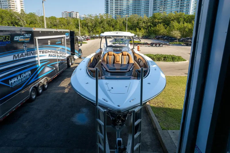 Slide: The Image of 2022 MTI V50 boat on trailer, parked near a building with cityscape background. - 45
