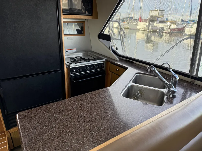 Slide: The Image of Bayliner 4087 Aft Cabin Motoryacht 2002 kitchen with sink, stove, and marina view. - 15
