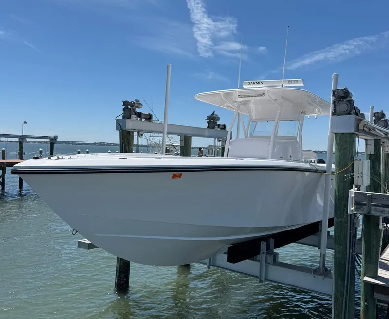Slide: The Image of 1998 Venture Center Console boat docked on a lift under a clear blue sky. - 0