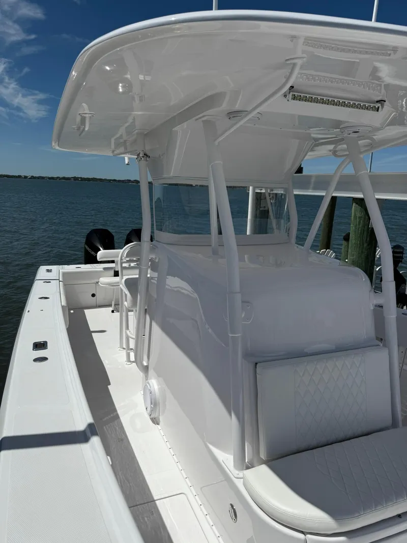 Slide: The Image of 1998 Venture Center Console boat with white seating, docked by calm waters under a clear blue sky. - 3