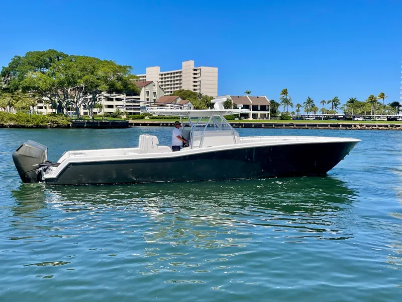 The Image of 2014 Invincible 42 Open Fisherman boat on calm water, with buildings and trees in the background. - 0