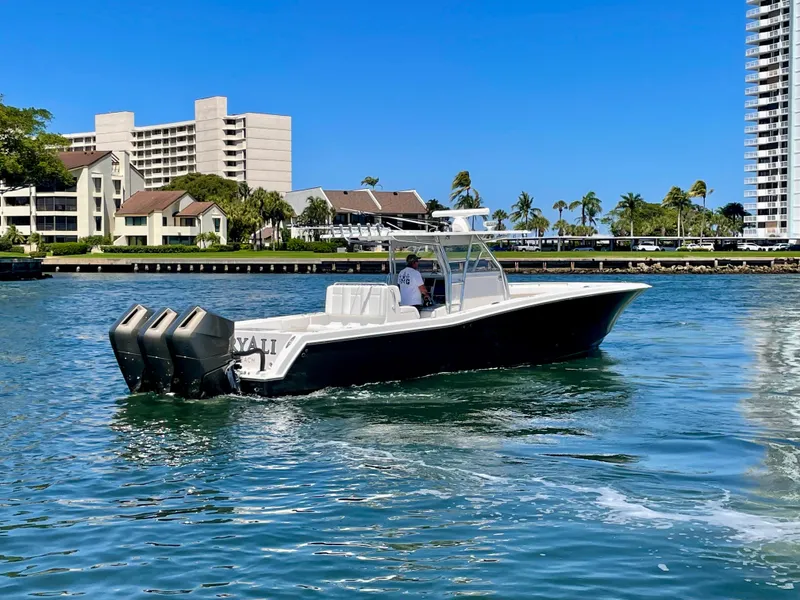 Slide: The Image of 2014 Invincible 42 Open Fisherman boat cruising near waterfront buildings. - 28