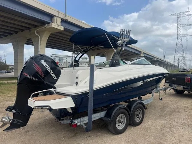 Slide: The Image of 2014 Sea Ray 220 SD Outboard boat on trailer, parked under a bridge. - 2