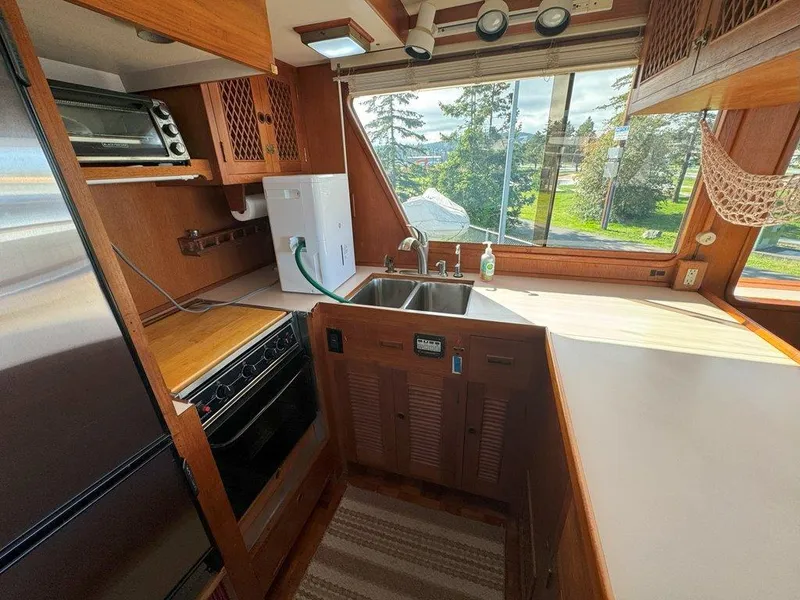 Slide: The Image of 1980 Ocean Alexander 50 MK1 yacht kitchen with wood cabinetry, sink, and large window view. - 10
