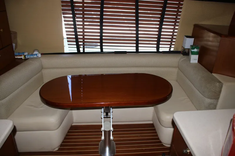 Slide: The Image of Interior of a 1999 Ocean Yachts model, featuring a wooden table and cushioned seating. - 4