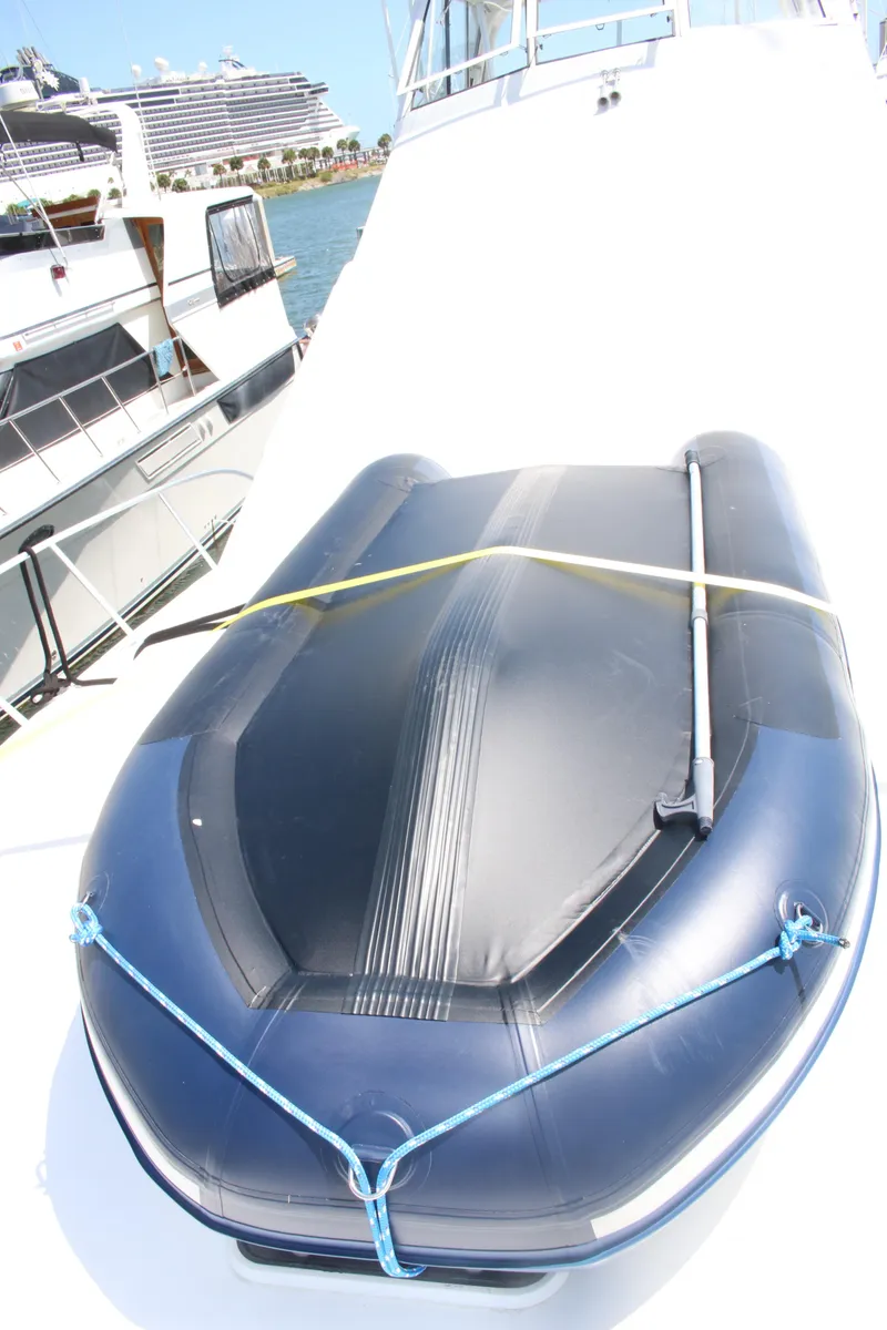 Slide: The Image of 1999 Ocean Yachts model with inflatable boat on deck, docked near other yachts. - 14
