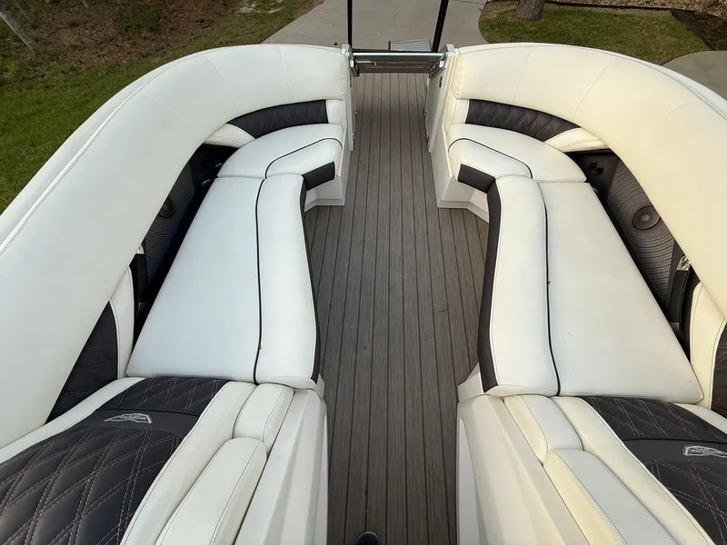 Slide: The Image of 2019 Bennington 25 QX Sport boat interior with white cushioned seating and wood-style flooring. - 20