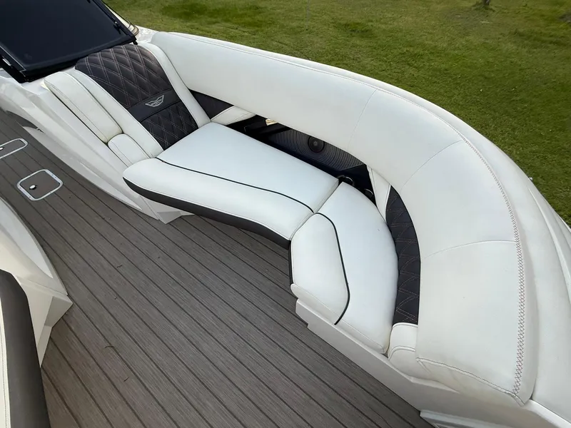 Slide: The Image of 2019 Bennington 25 QX Sport boat interior with white and black seating on wooden deck. - 21