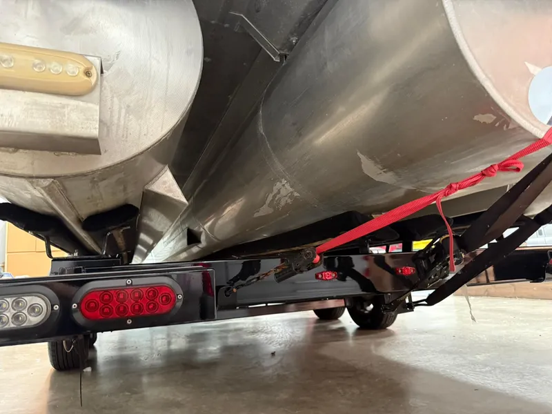 Slide: The Image of 2019 Bennington 25 QX Sport pontoon boat underside with trailer and red strap. - 28