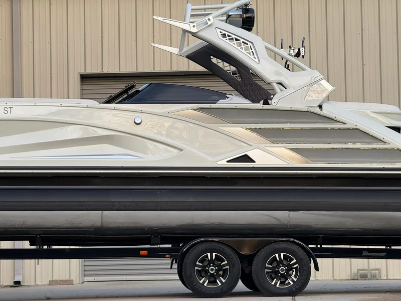 Slide: The Image of 2019 Bennington 25 QX Sport boat on trailer, side view, against a beige building. - 3