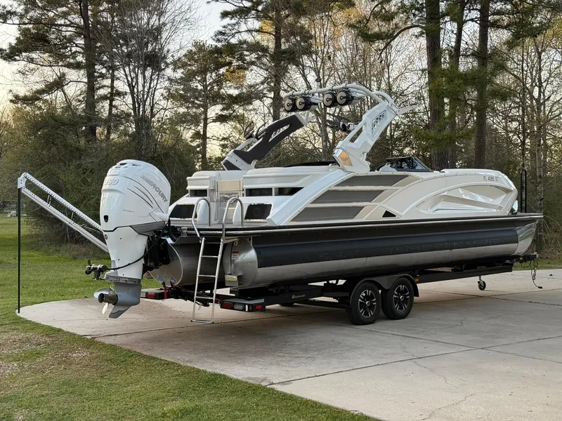 Slide: The Image of 2019 Bennington 25 QX Sport pontoon boat on trailer, parked outdoors. - 6