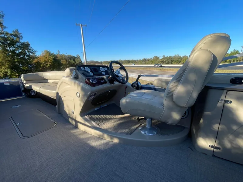 Slide: The Image of 2017 Regency 220 DL3 boat interior with steering console and seating, under clear blue sky. - 11