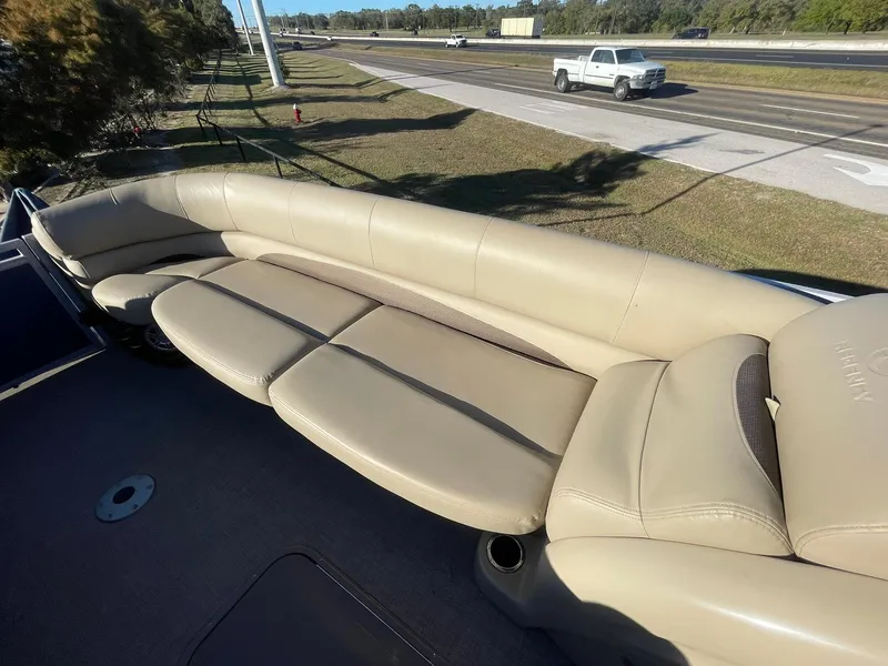 Slide: The Image of 2017 Regency 220 DL3 boat with beige seating, parked near a highway. - 15