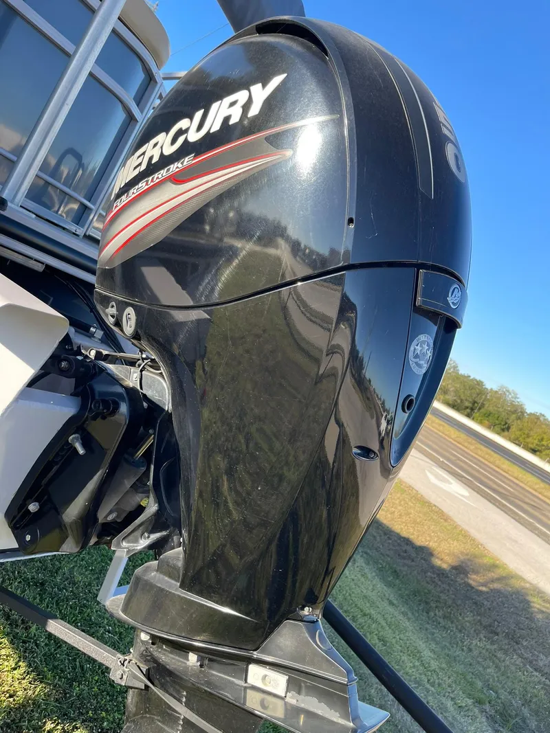 Slide: The Image of 2017 Regency 220 DL3 boat with Mercury outboard motor, parked on grass. - 18