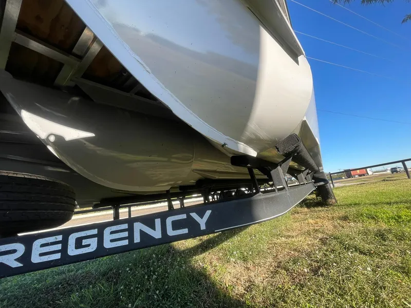 Slide: The Image of 2017 Regency 220 DL3 boat on trailer, viewed from below, on grassy area. - 34