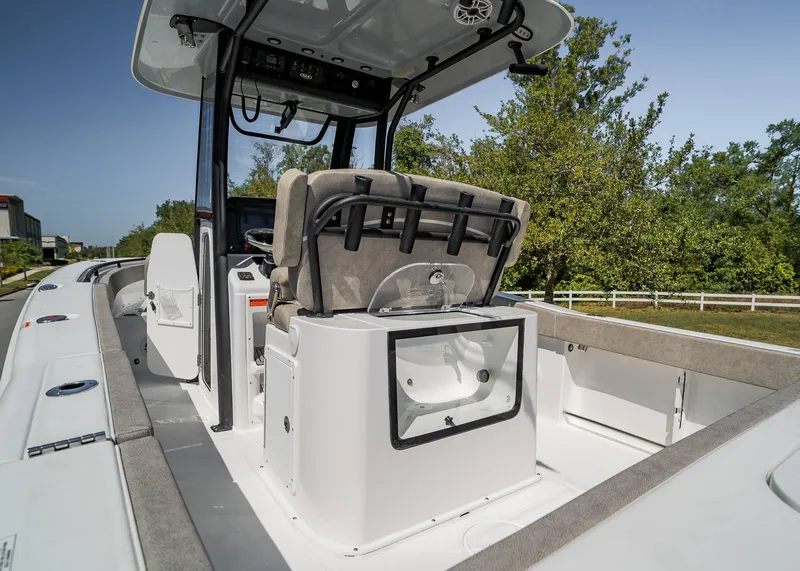 Slide: The Image of 2025 Sea Hunt Gamefish 25 boat interior with seating and storage, surrounded by greenery. - 18