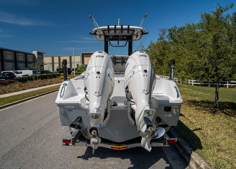 Slide: The Image of 2025 Sea Hunt Gamefish 25 boat with dual outboard motors, parked on a sunny street. - 4