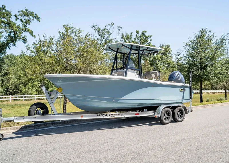 Slide: The Image of 2025 Sea Hunt Ultra 219 boat on trailer, parked on a sunny road. - 1