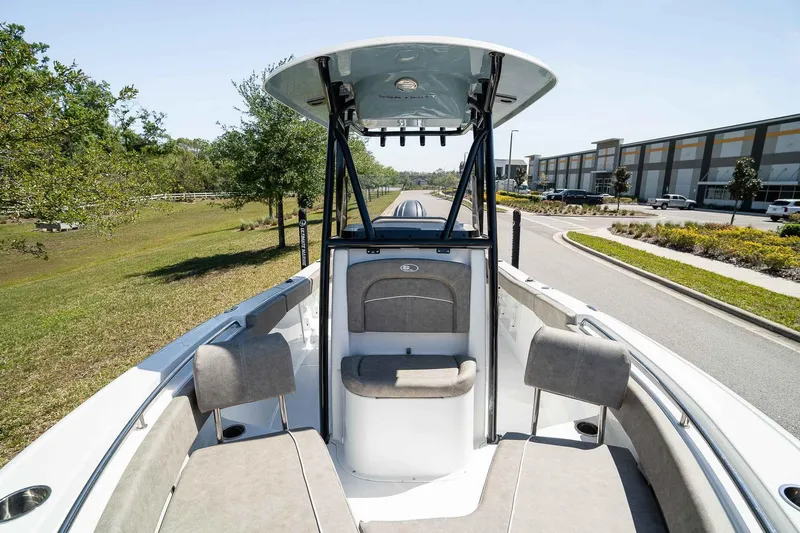 Slide: The Image of 2025 Sea Hunt Ultra 219 boat interior with seating and canopy, parked near greenery and buildings. - 15