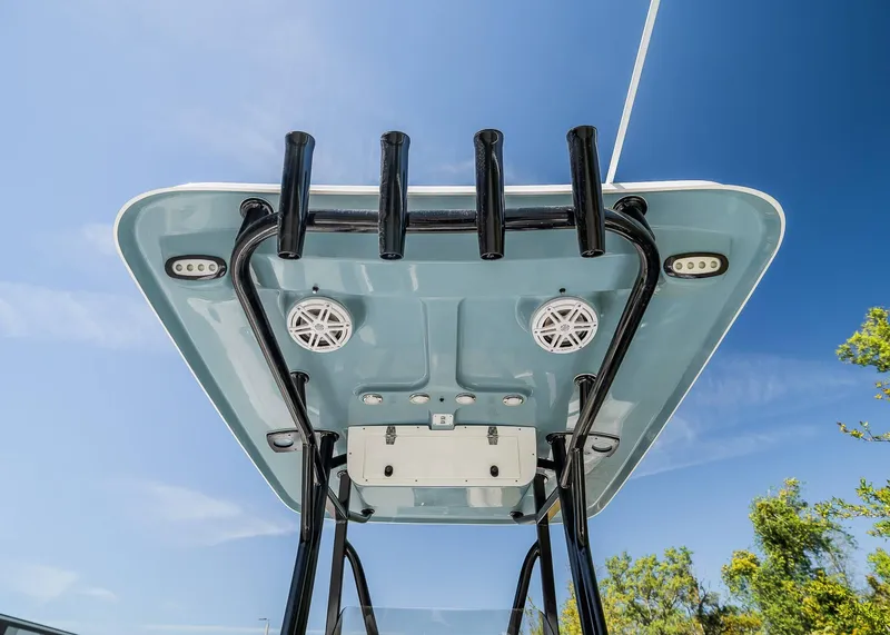 Slide: The Image of 2025 Sea Hunt Ultra 219 boat T-top with rod holders and speakers against blue sky. - 18