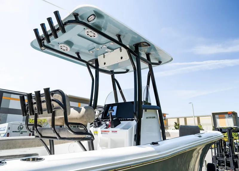 Slide: The Image of 2025 Sea Hunt Ultra 219 boat with T-top and rod holders under a clear sky. - 6
