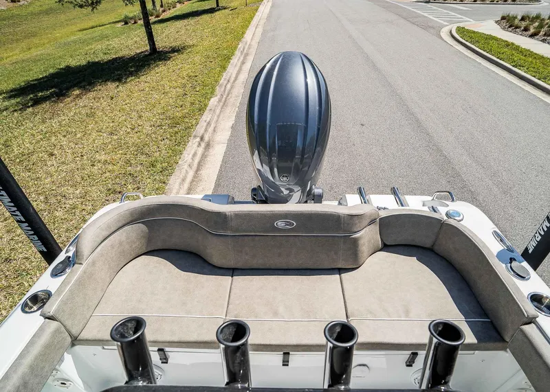 Slide: The Image of 2025 Sea Hunt Ultra 219 boat with cushioned seating and outboard motor on a sunny day. - 7