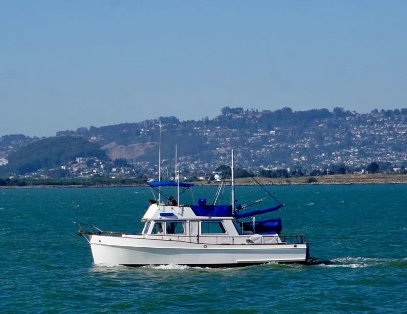 Slide: The Image of 1982 Grand Banks Classic boat cruising on a scenic lake with hills in the background. - 5