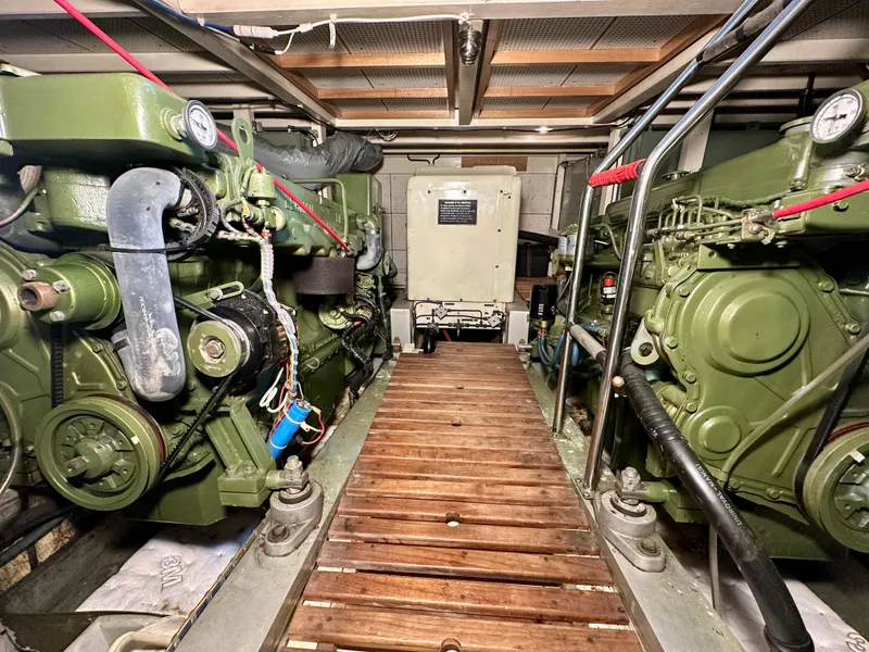 Slide: The Image of Engine room of 1982 Grand Banks Classic boat with dual green engines and wooden walkway. - 51