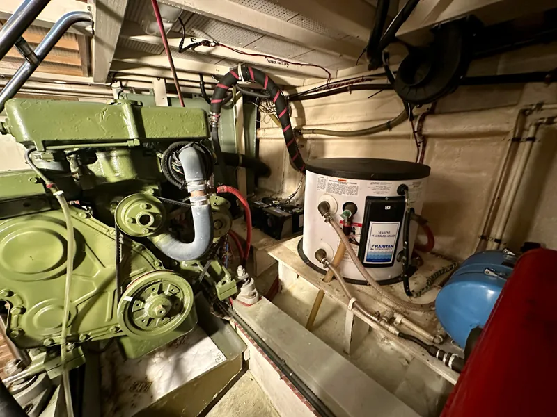 Slide: The Image of Engine room of a 1982 Grand Banks Classic boat, featuring machinery and piping. - 56