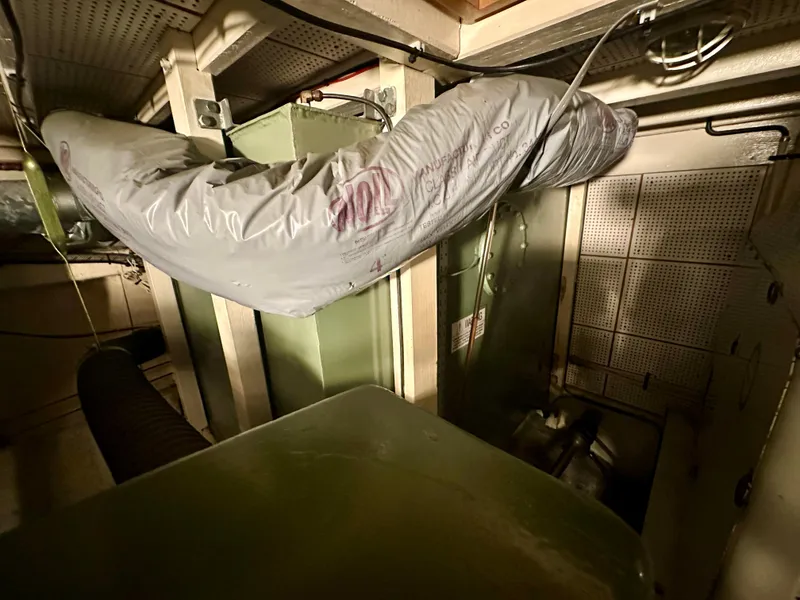 Slide: The Image of Engine room of a 1982 Grand Banks Classic boat, featuring machinery and ductwork. - 59