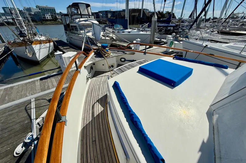 Slide: The Image of 1982 Grand Banks 42 Classic yacht docked at marina, featuring wooden railings and blue cushions. - 73