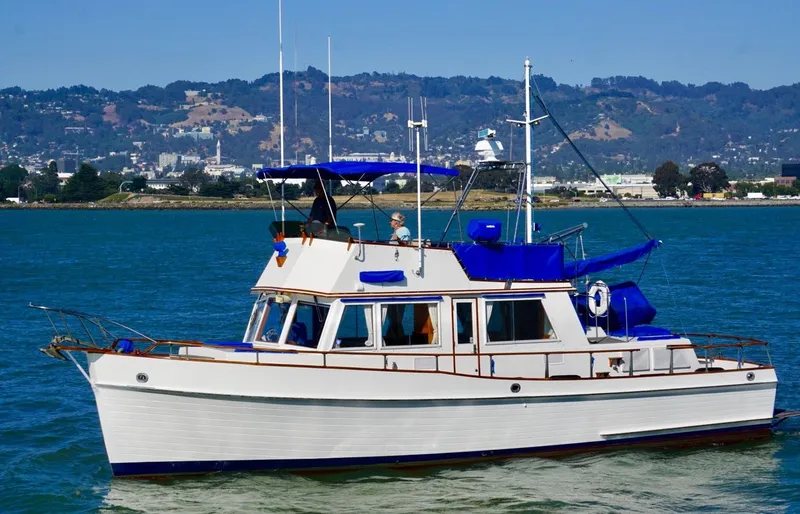 The Image of 1982 Grand Banks Classic yacht cruising on a scenic waterway with hills in the background. - 0