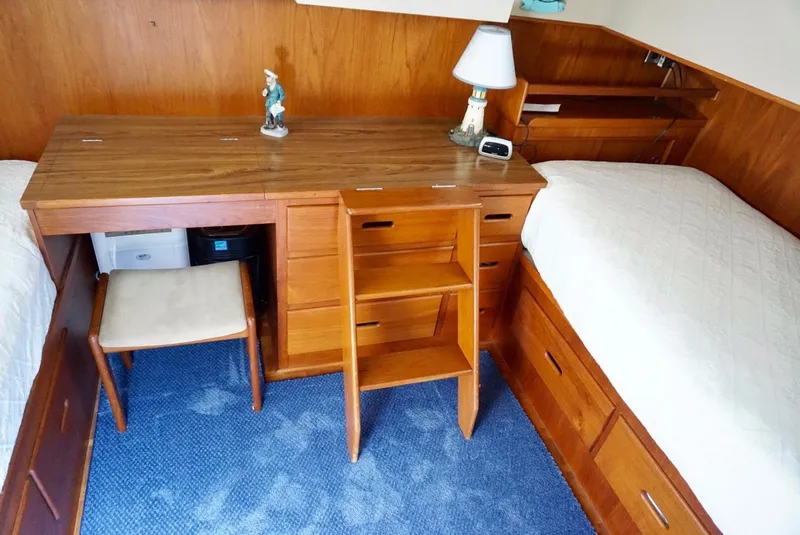 Slide: The Image of 1982 Grand Banks Classic cabin interior with wooden desk, twin beds, and blue carpet. - 15