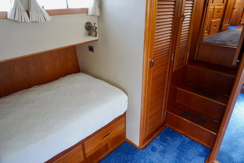 Slide: The Image of 1982 Grand Banks Classic interior with wooden cabinetry, cozy bed, and blue carpeted flooring. - 17
