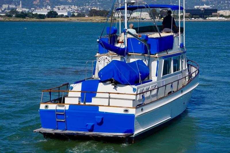 Slide: The Image of 1982 Grand Banks Classic yacht cruising on a sunny day, featuring blue and white design. - 4