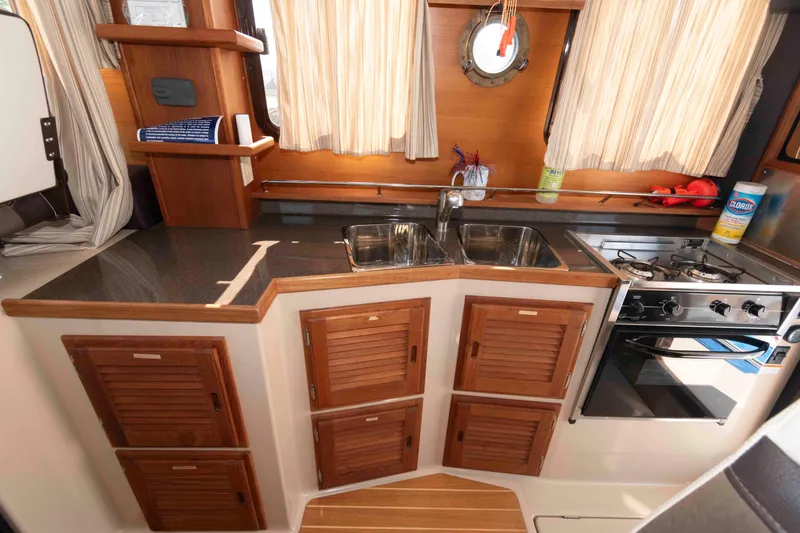 Slide: The Image of 2016 Ranger Tugs R-31S kitchen with wooden cabinets, dual sink, and stove. - 18