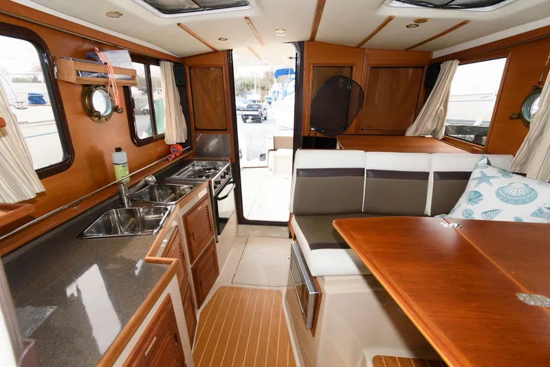 Slide: The Image of 2016 Ranger Tugs R-31S interior with kitchen, dining area, and wood finishes. - 19