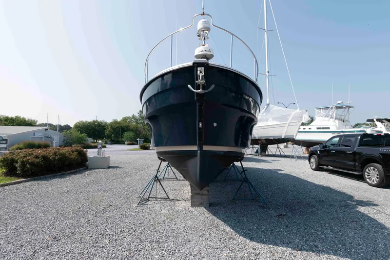 Slide: The Image of 2016 Ranger Tugs R-31S boat on stands in a gravel lot, surrounded by other boats. - 7