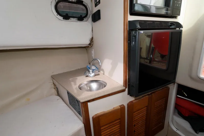 Slide: The Image of 2000 Pursuit 3070 Offshore Center Console interior with sink and compact kitchen area. - 17