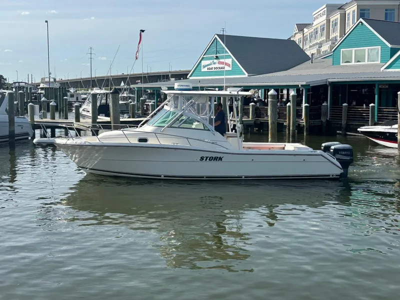 Slide: The Image of 2000 Pursuit 3070 Offshore Center Console boat docked near marina buildings. - 2