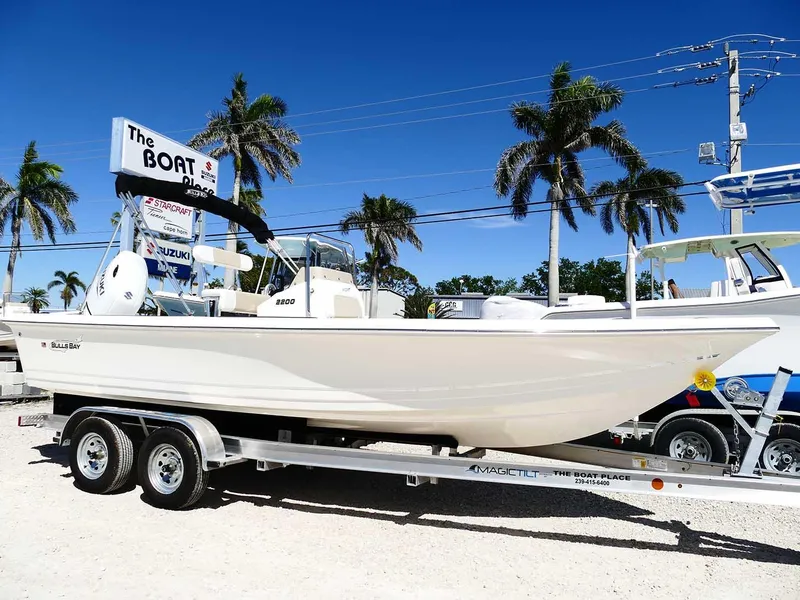 Slide: The Image of 2025 Bulls Bay 2200 boat on trailer, displayed outdoors with palm trees in the background. - 0