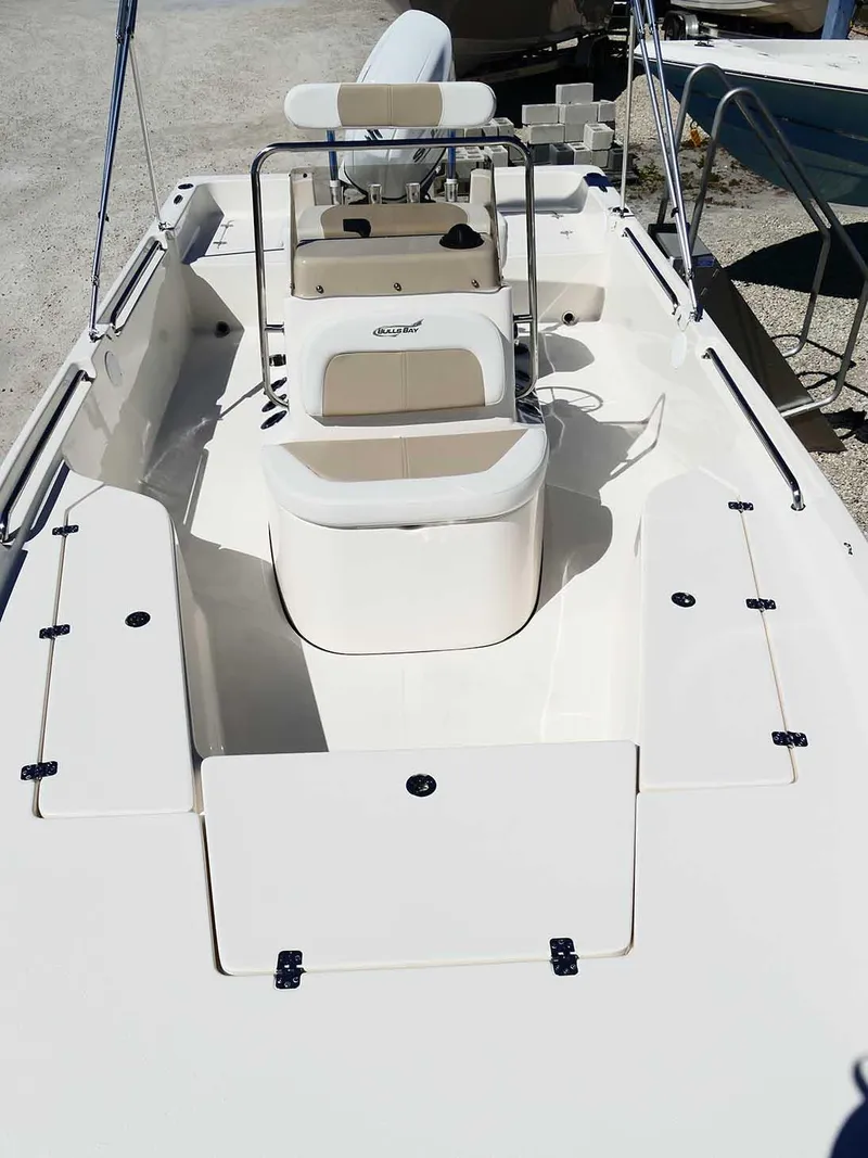 Slide: The Image of 2025 Bulls Bay 2200 boat interior with seating and console, docked on gravel. - 23