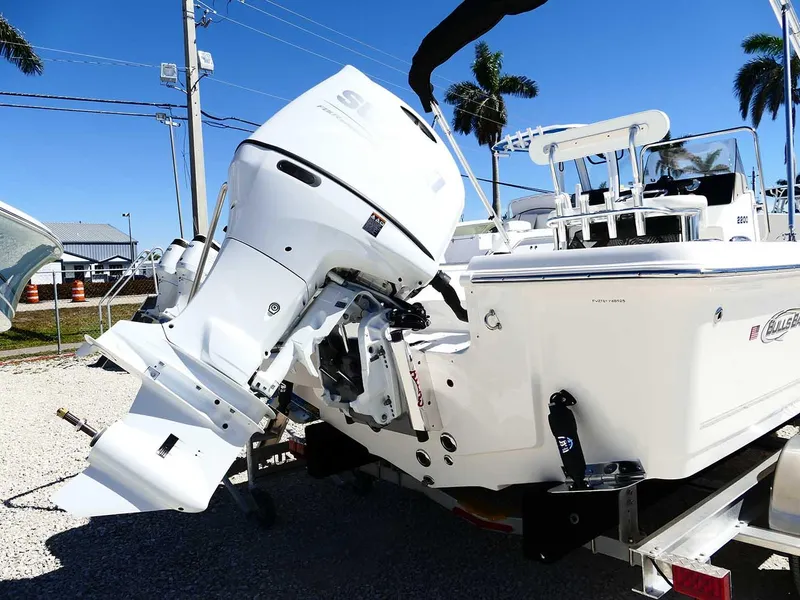 Slide: The Image of 2025 Bulls Bay 2200 boat with outboard motor on a trailer, under clear blue sky. - 7