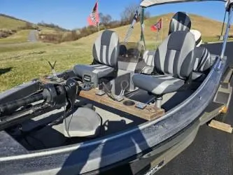 Slide: The Image of 1989 Bomber Crappie Mate fishing boat with striped seats and trolling motor on a sunny day. - 6