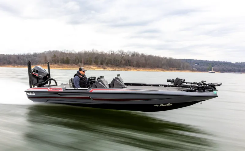 Slide: The Image of 2026 Bass Cat Lynx STS boat speeding on a lake with a driver. - 0