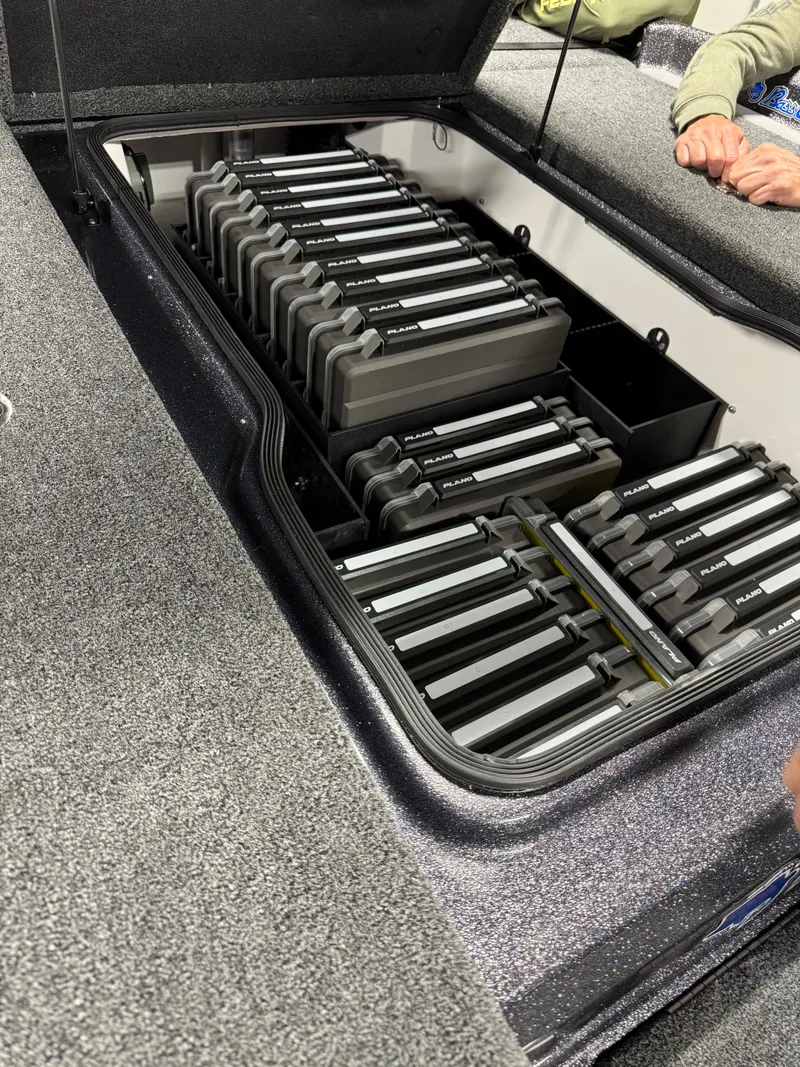 Slide: The Image of 2026 Bass Cat Lynx STS storage compartment with organized tackle boxes. - 13