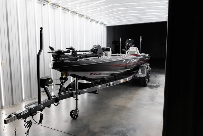 Slide: The Image of 2026 Bass Cat Lynx STS boat in a well-lit garage on a trailer. - 6
