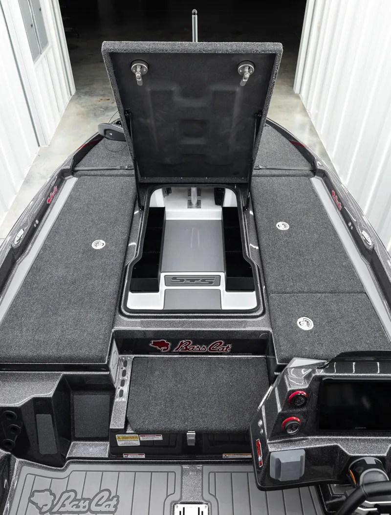 Slide: The Image of 2026 Bass Cat Lynx STS boat interior with open storage compartment and control panel. - 9